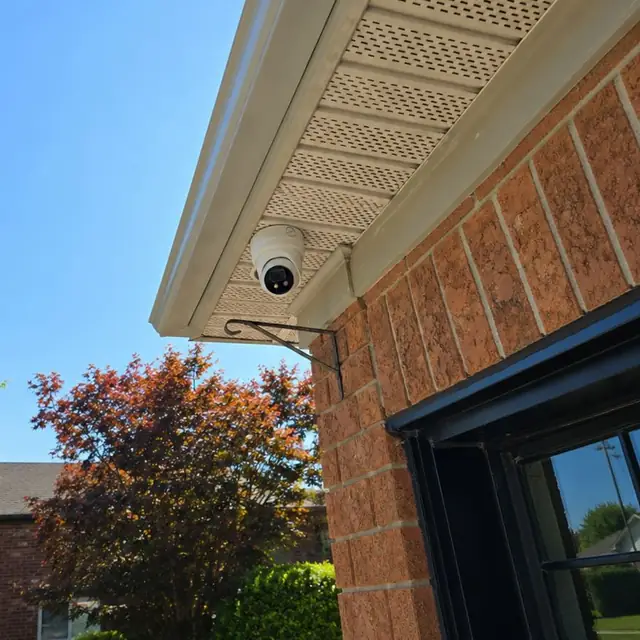 Dome camera under the eaves of a red-brick home