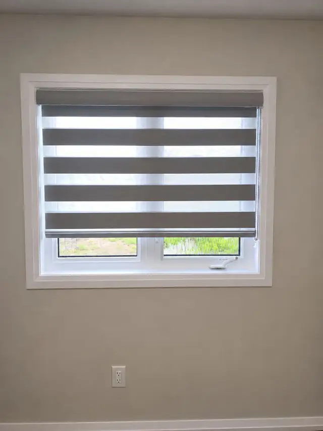 Zebra blind fitted to a single window on a grey wall